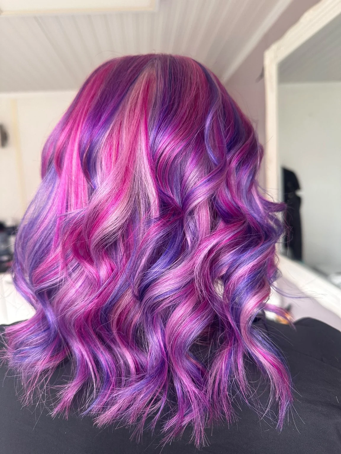 Vibrant pink and purple hair styled in waves