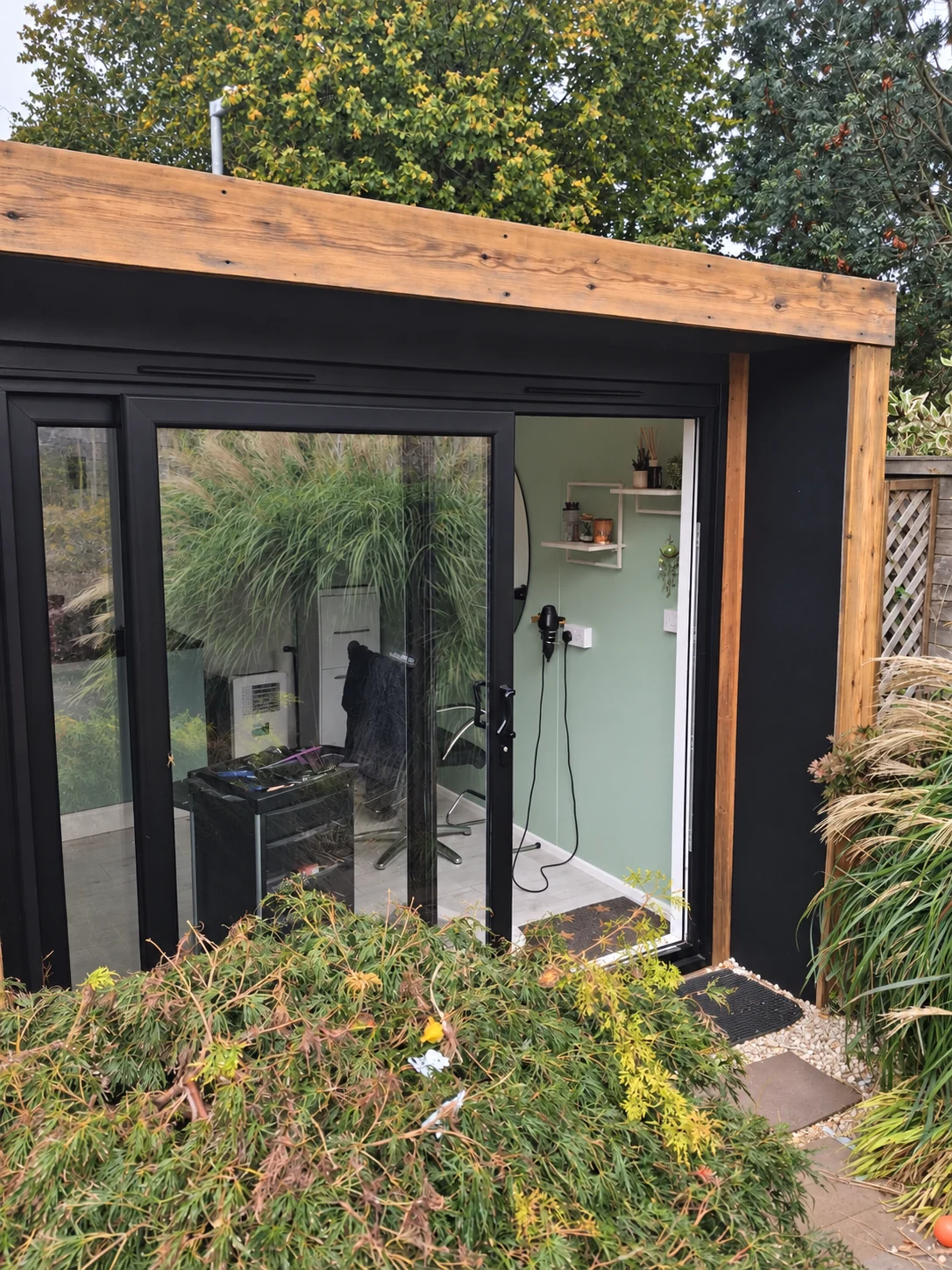 My black timber garden salon, with sliding glass doors opening onto the garden